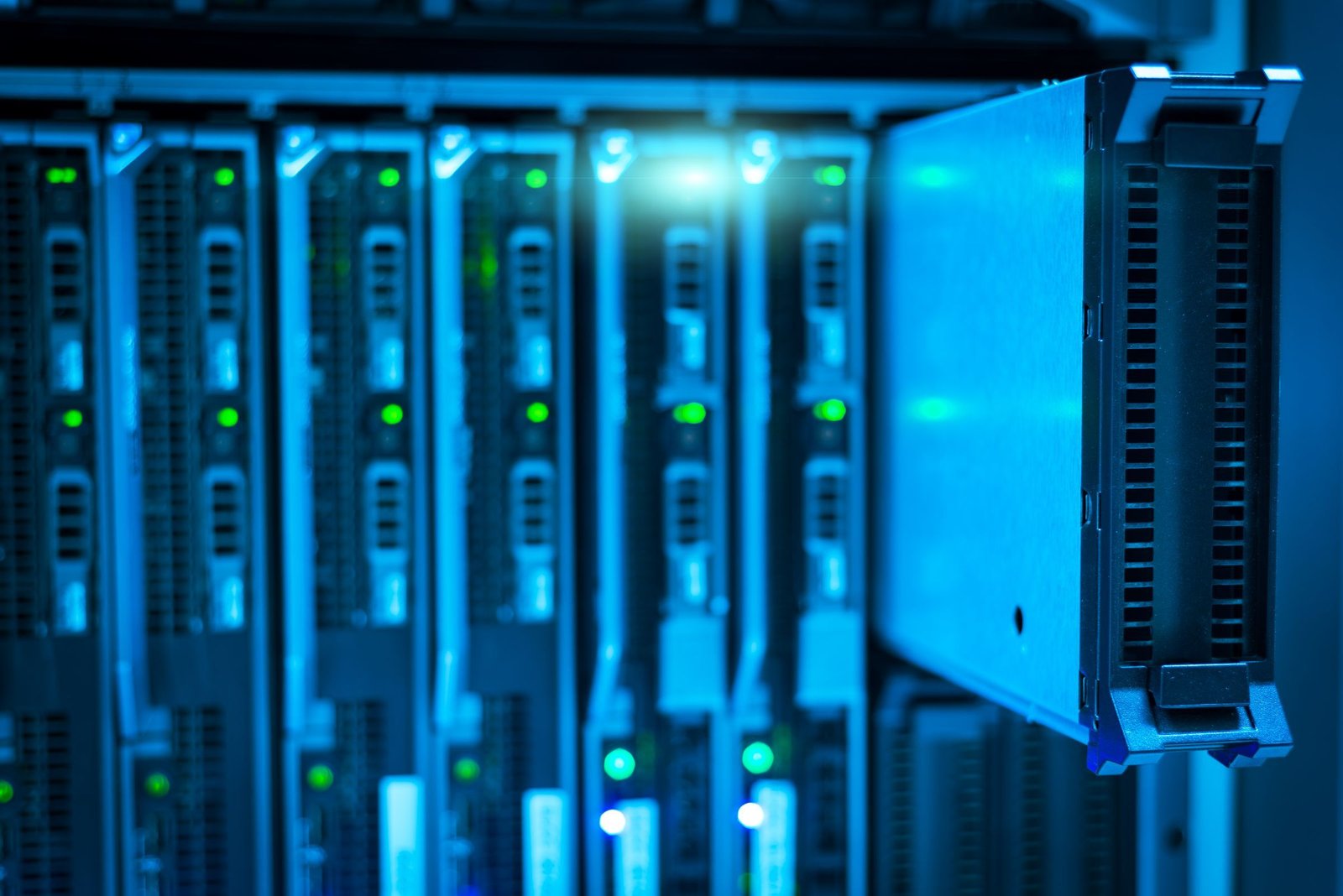 A single blade server pulled forward from a row of identical units in a rack, lit in cool blue with green status lights