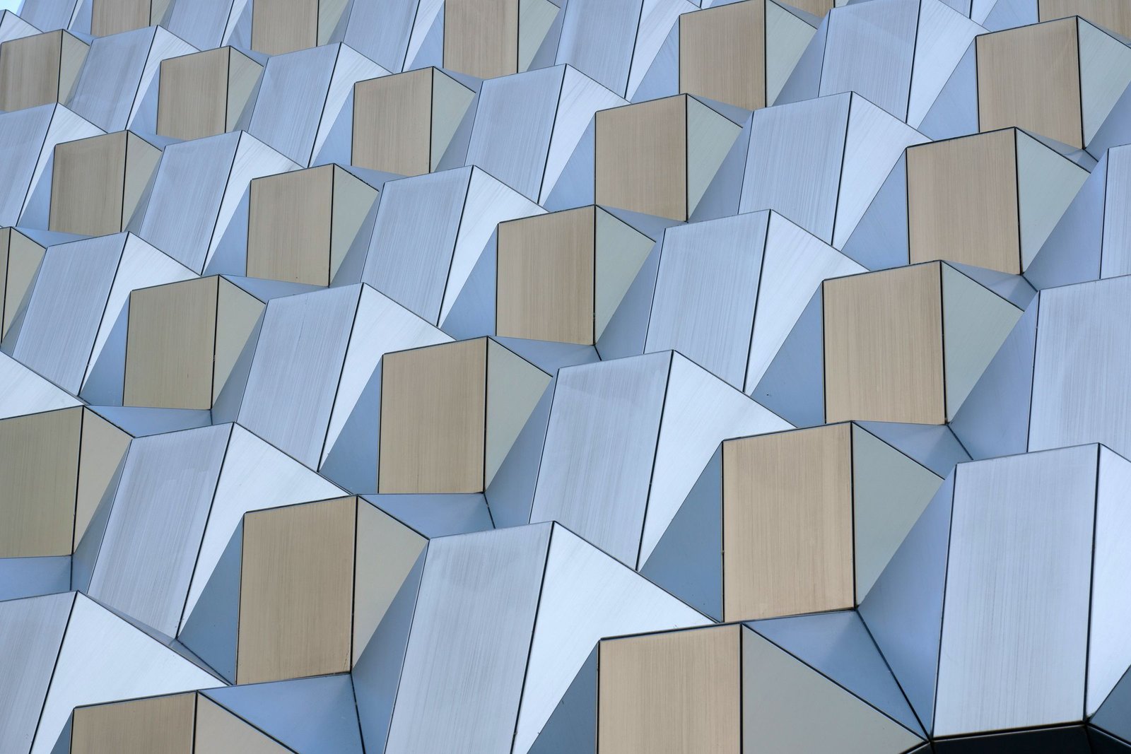 Brushed metal facets and beige square panels repeating row upon row across a modern building facade